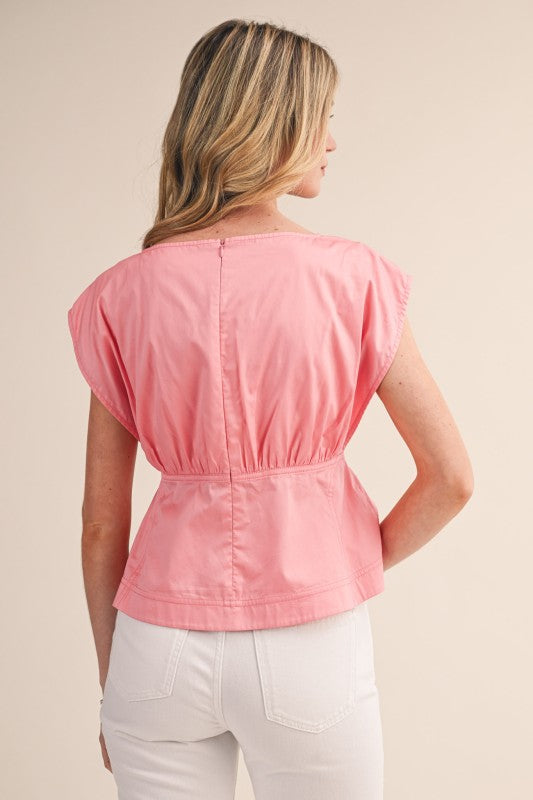 Woman wearing a pink top and white pants on a beige background