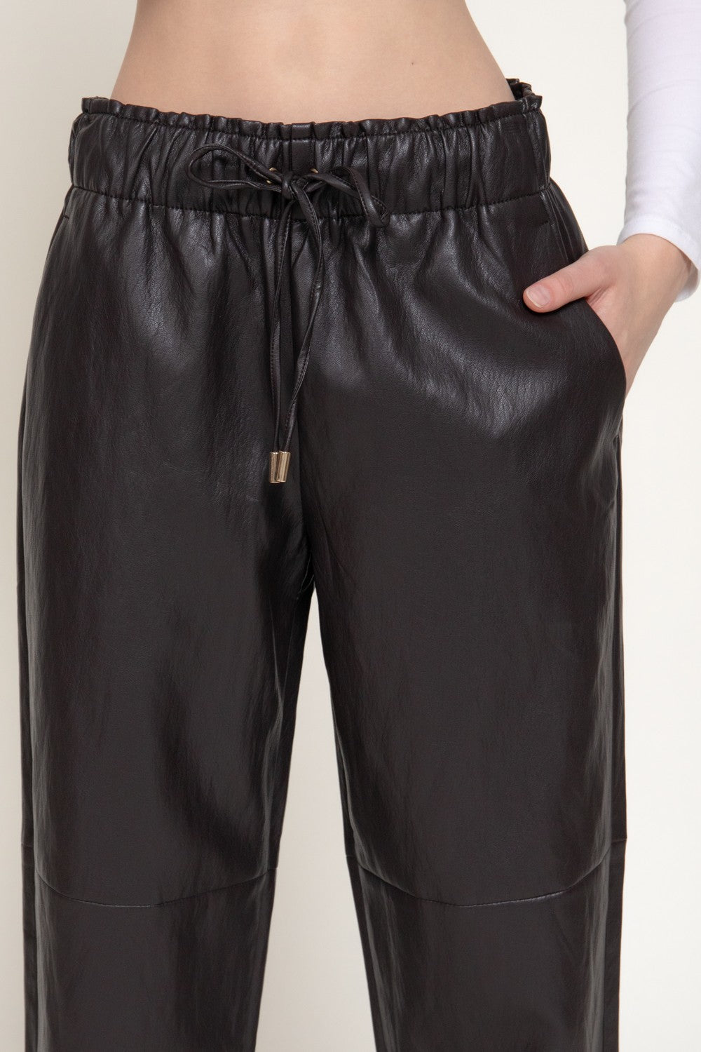 Black faux leather drawstring pants with an elastic waistband, shown on a model against a light background.