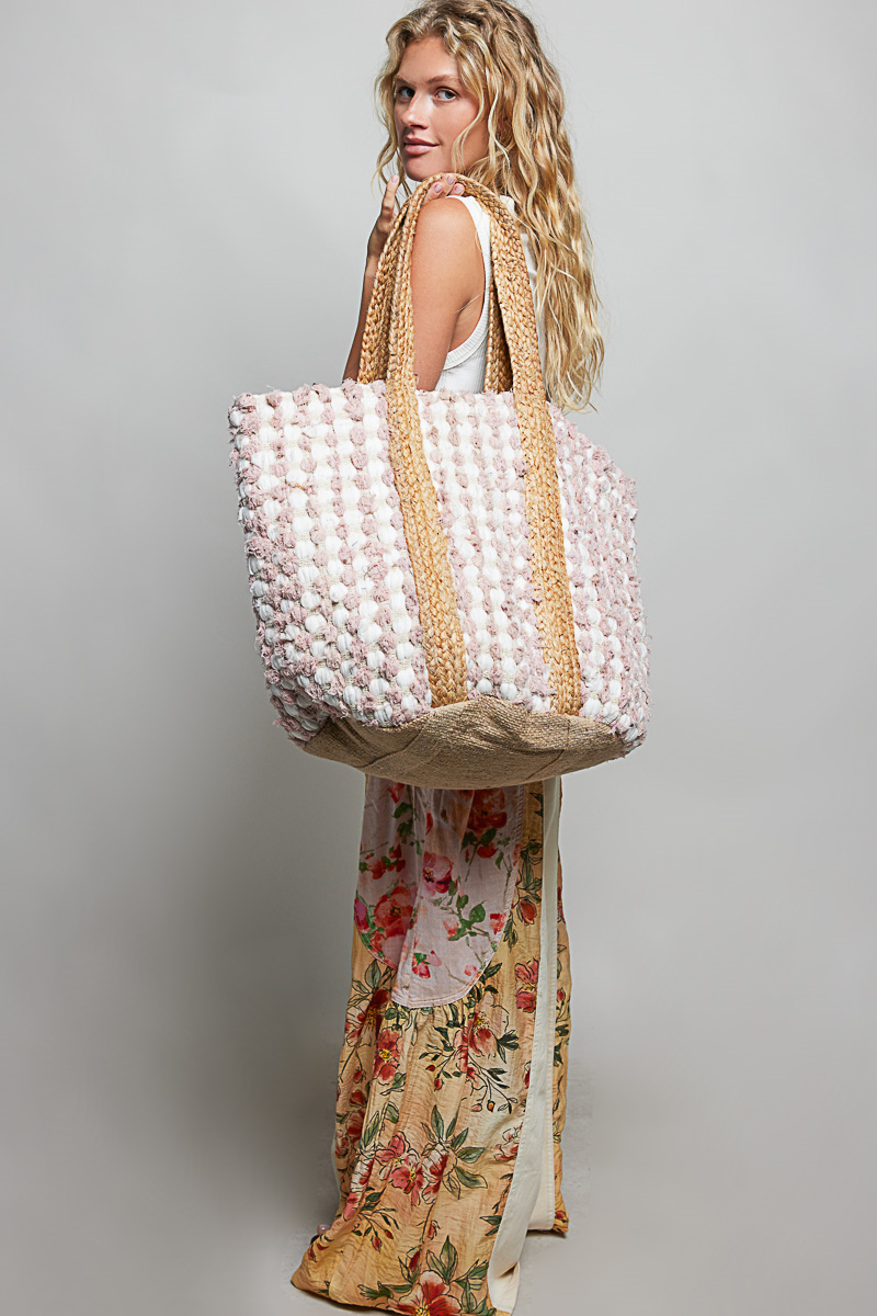 Woman holding a large woven bag against a plain background