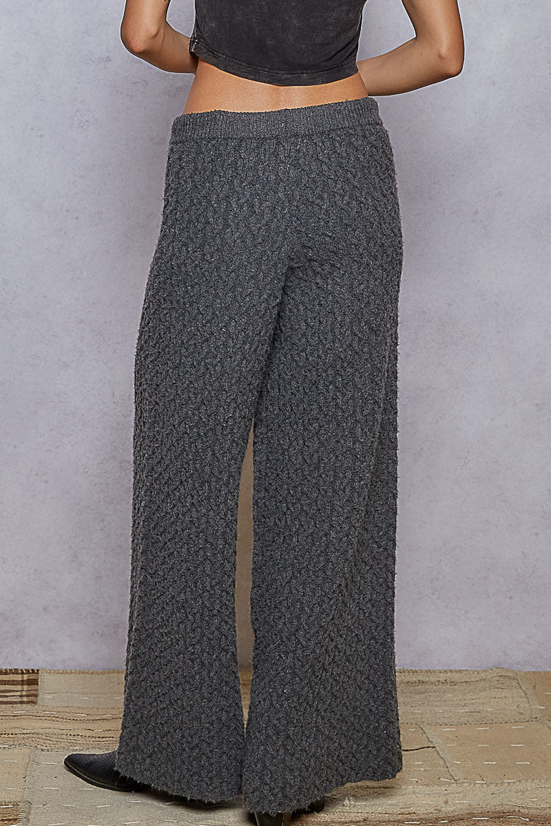 Person wearing gray patterned pants against a plain background
