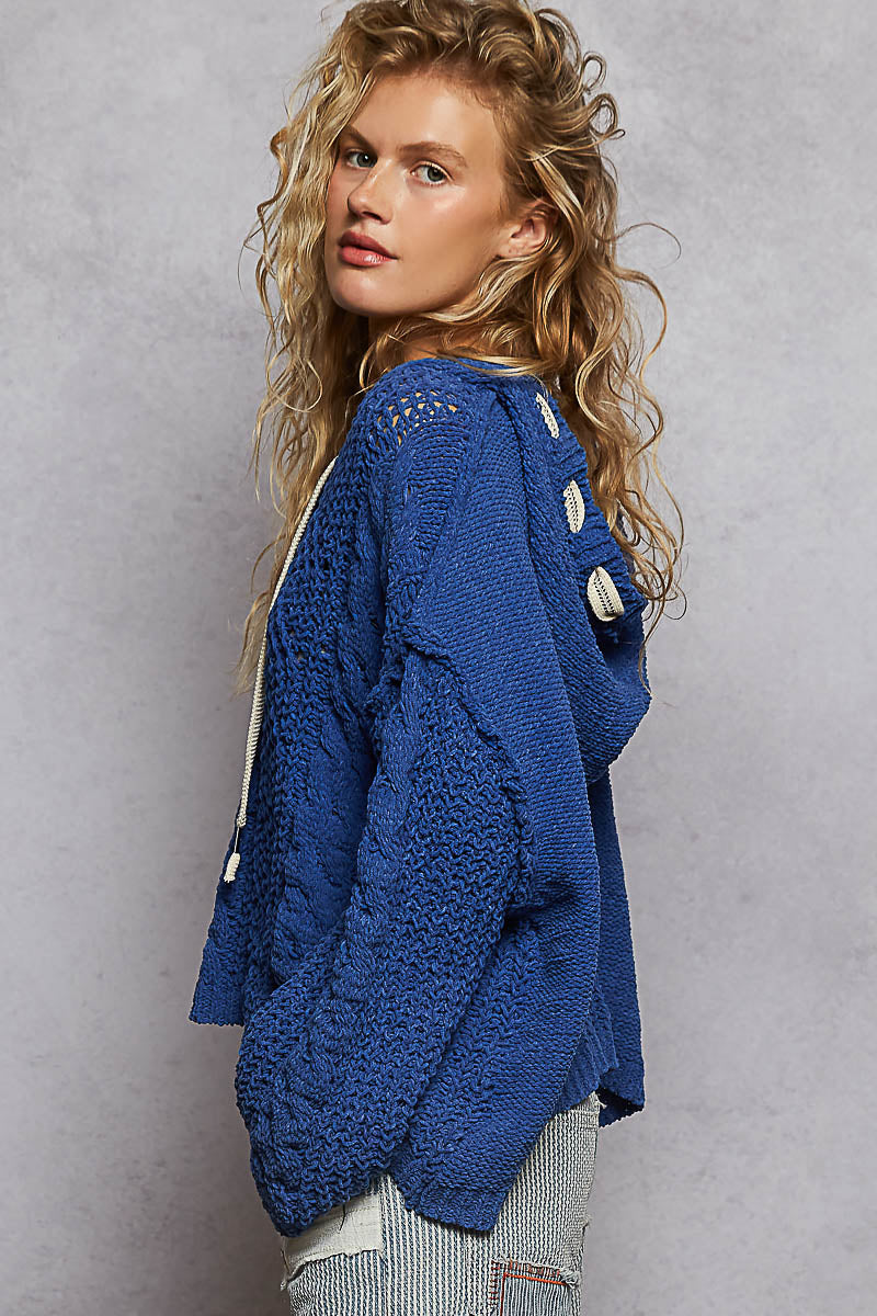 Woman wearing a blue knitted cardigan against a gray background