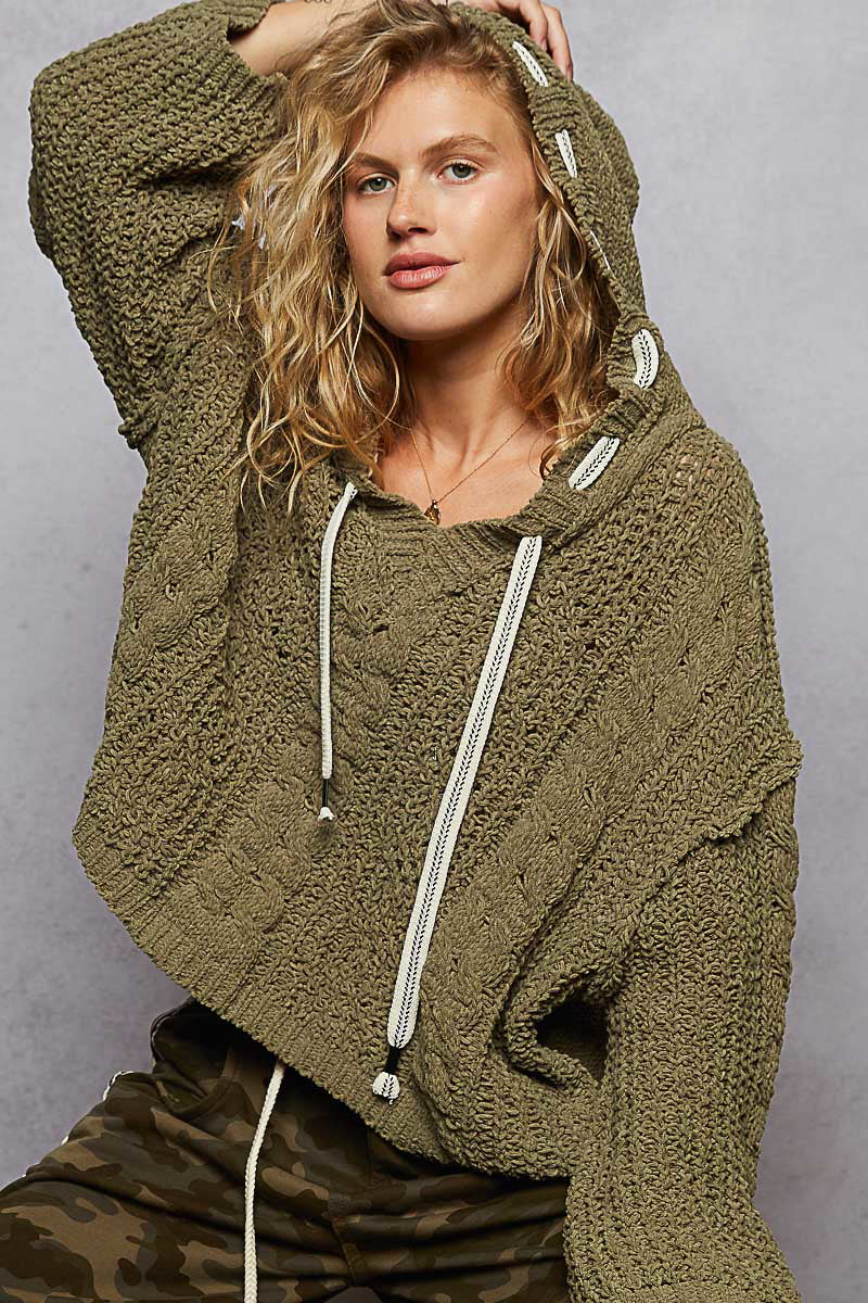 Woman wearing a green knitted hoodie against a gray background
