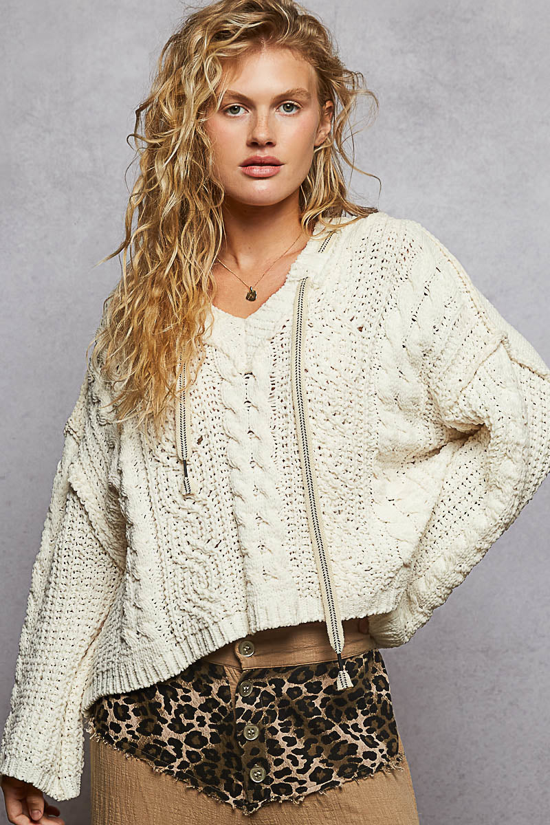 Woman wearing a cream-colored knit sweater with a zipper and leopard print shorts against a gray background