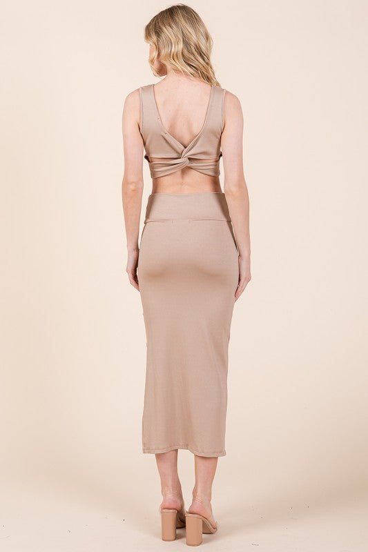 Woman wearing a beige dress with a open back on a plain background