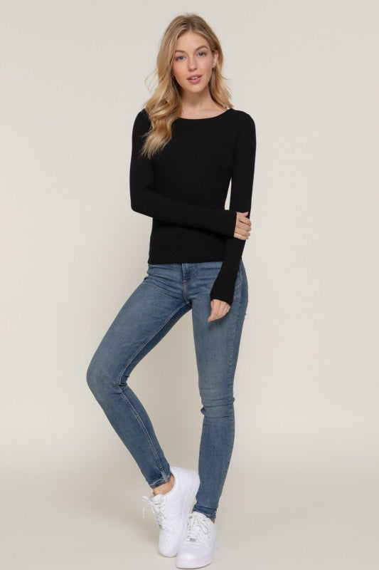 Woman wearing a black sweater and blue jeans on a plain background