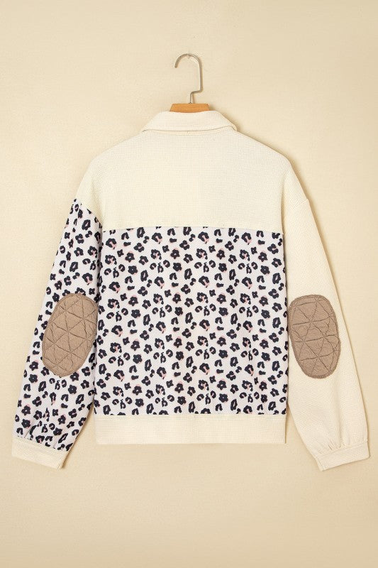 White sweater with leopard print pattern and elbow patches on a beige background