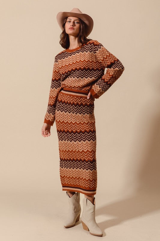 Woman wearing a patterned sweater dress and hat against a beige background