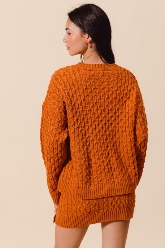 Woman wearing a brown knitted sweater and skirt set against a beige background