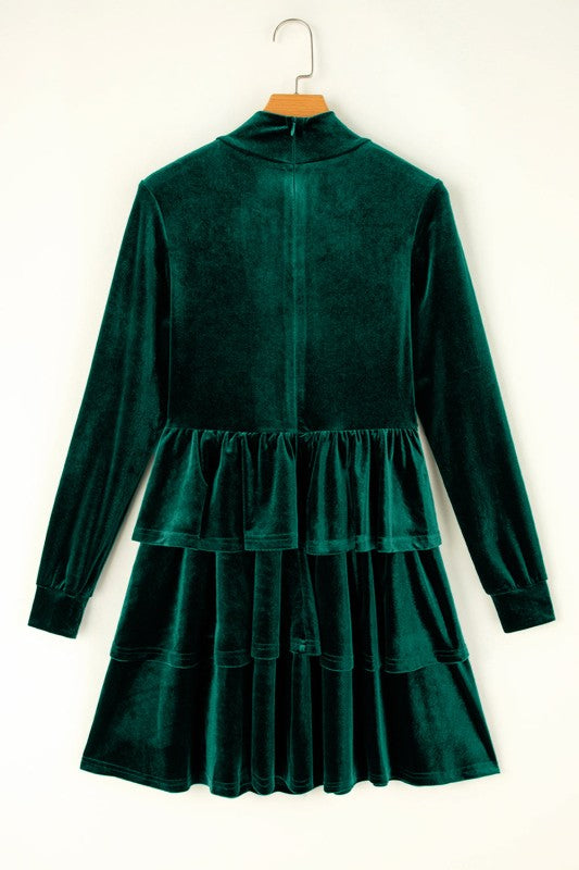 Green velvet dress on a hanger against a white background