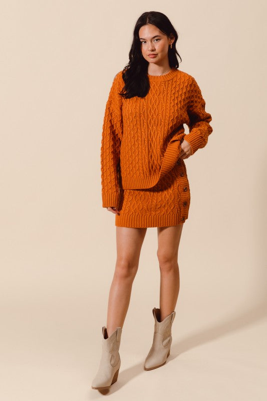 Woman wearing an orange knitted sweater and skirt set with white boots on a beige background