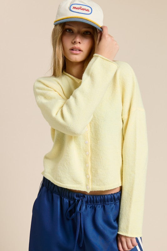 Person wearing a light yellow sweater and blue pants with a beige background