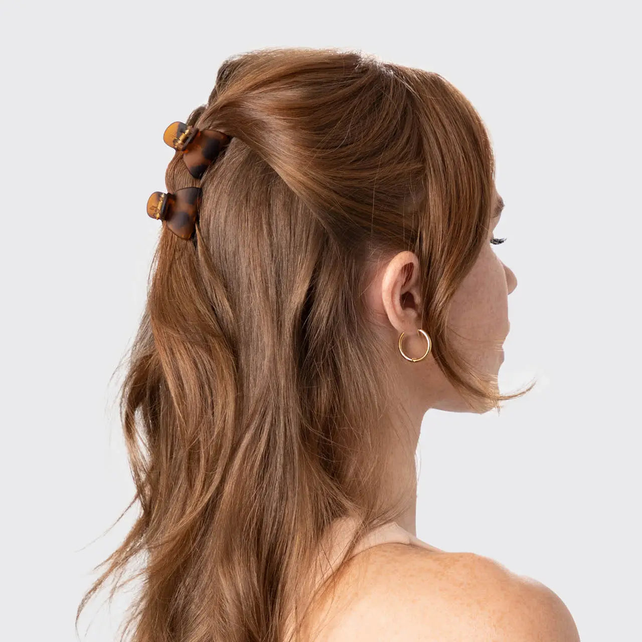 Woman with styled hair featuring a hair tie against a plain background