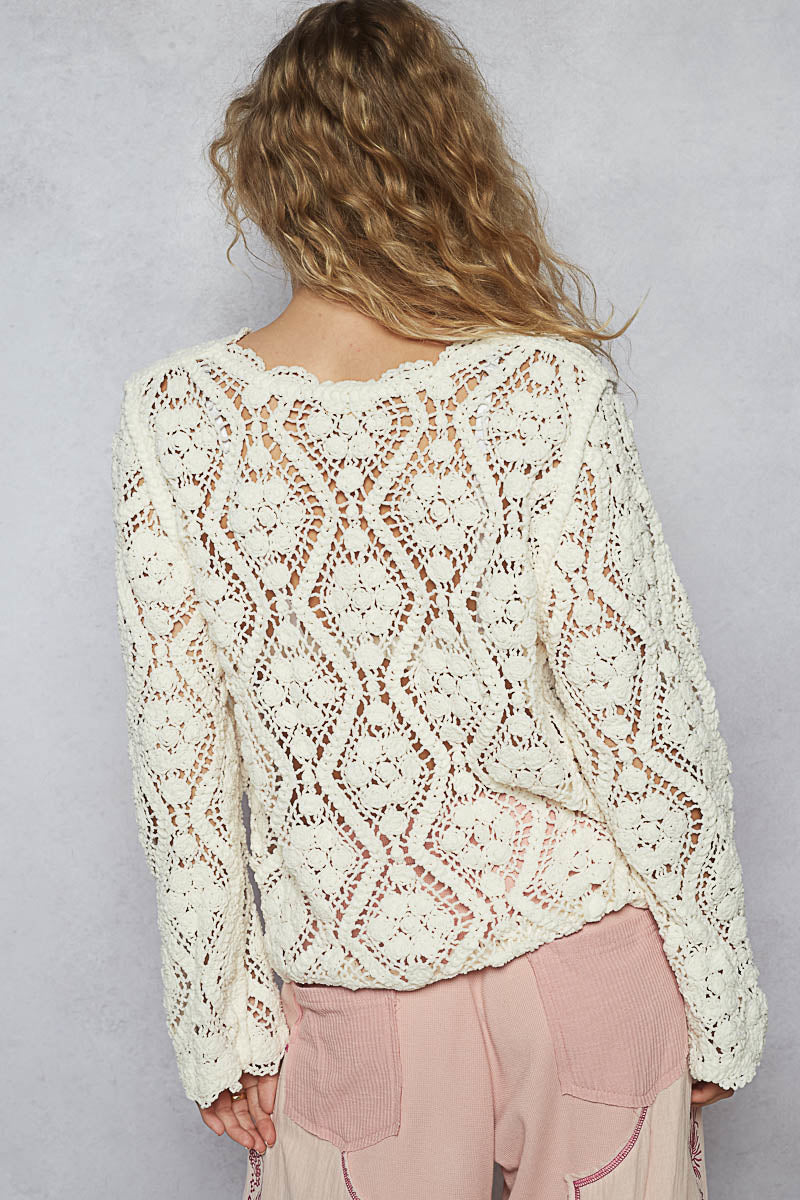 Person wearing a white lace sweater against a gray background