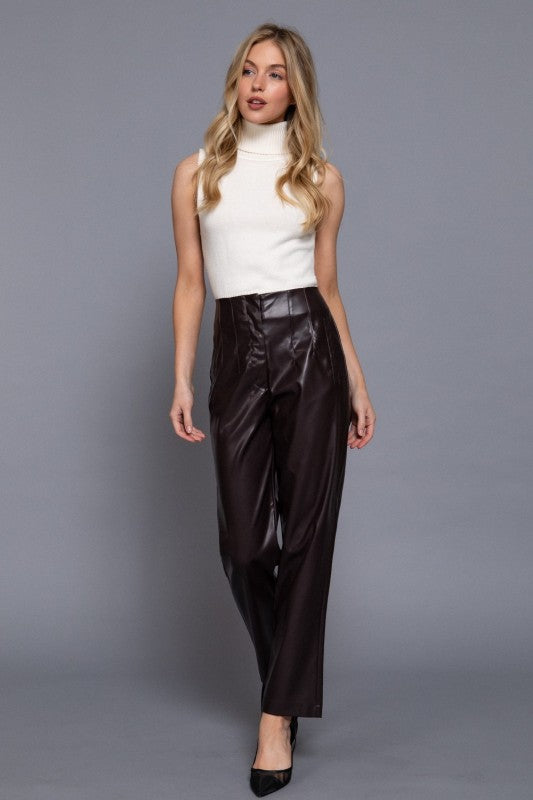 Woman wearing a white sleeveless top and black pants against a gray background