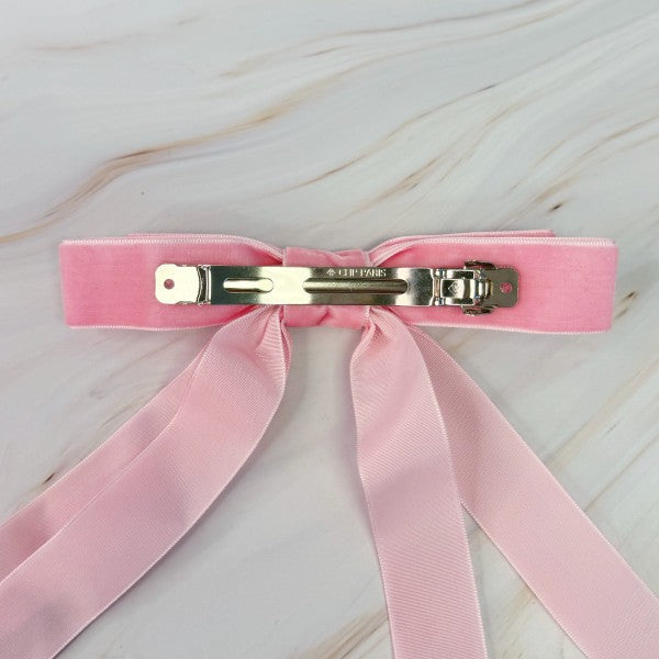 Pink hair clip with a bow on a light wooden surface