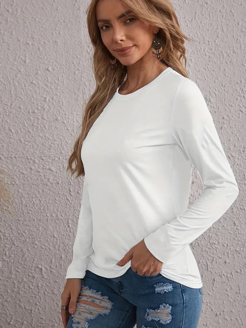 A woman wearing a white long sleeve t-shirt and blue denim jeans.