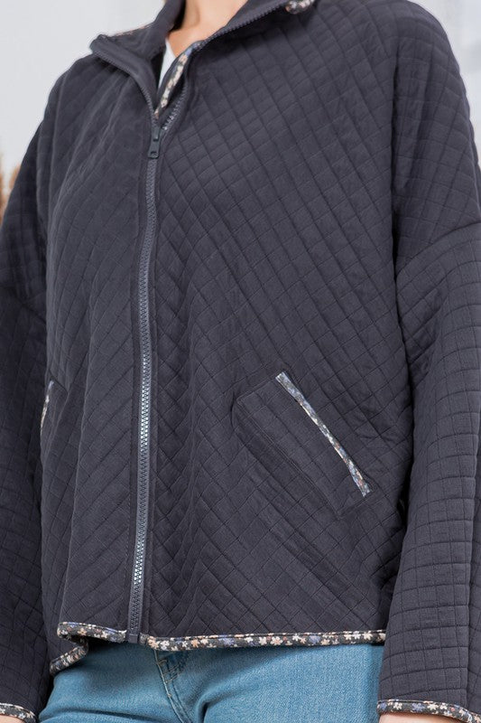 Quilted jacket with a zipper and pocket on a plain background