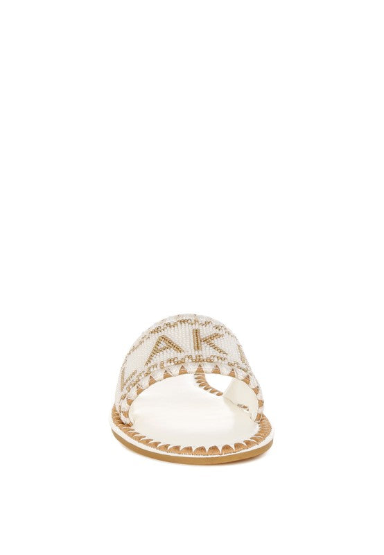 White sandal with gold embellishments on a white background