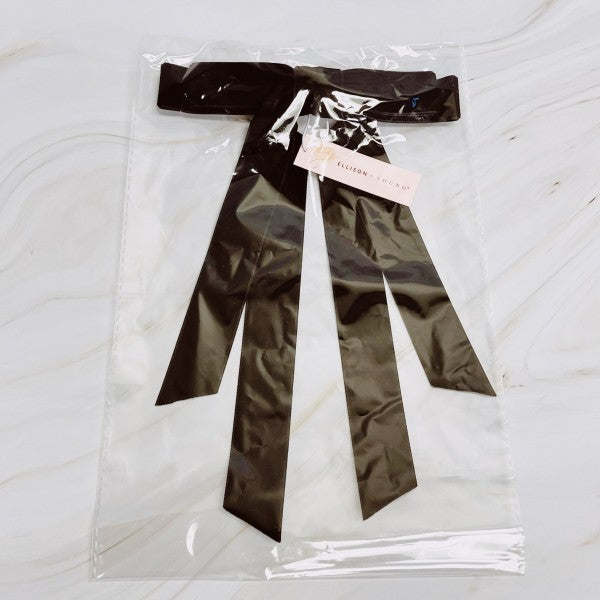 Black satin bow in clear packaging on a white marble surface