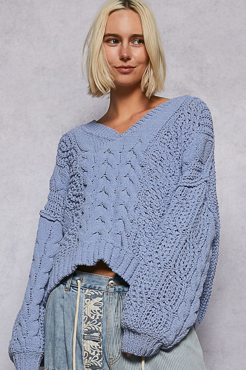 Woman wearing a blue knitted sweater against a plain background