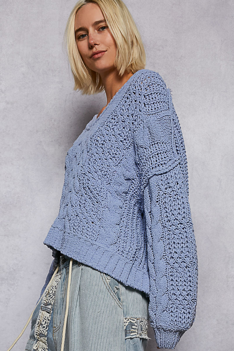 Woman wearing a blue knitted sweater against a plain background