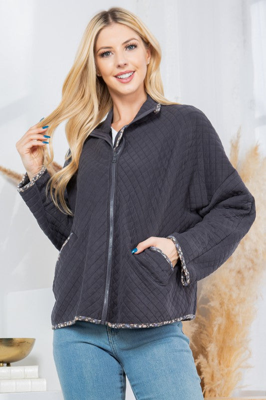 Woman wearing a dark gray quilted jacket with a white background
