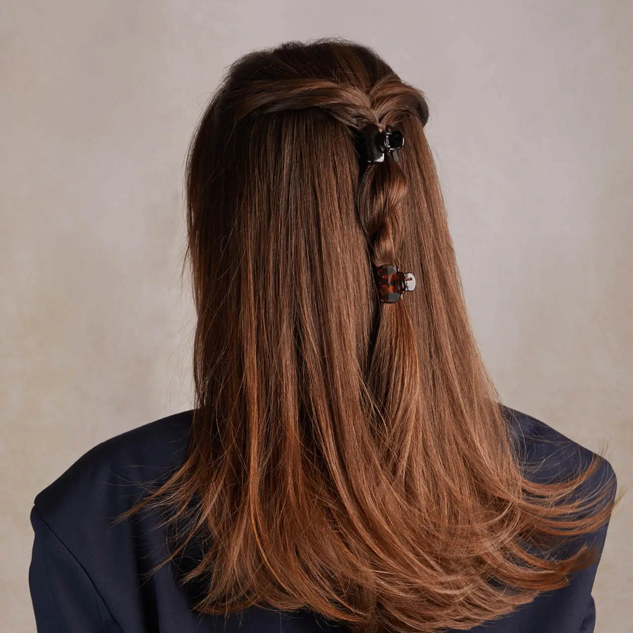 Long brown hair with a decorative hair clip against a neutral background