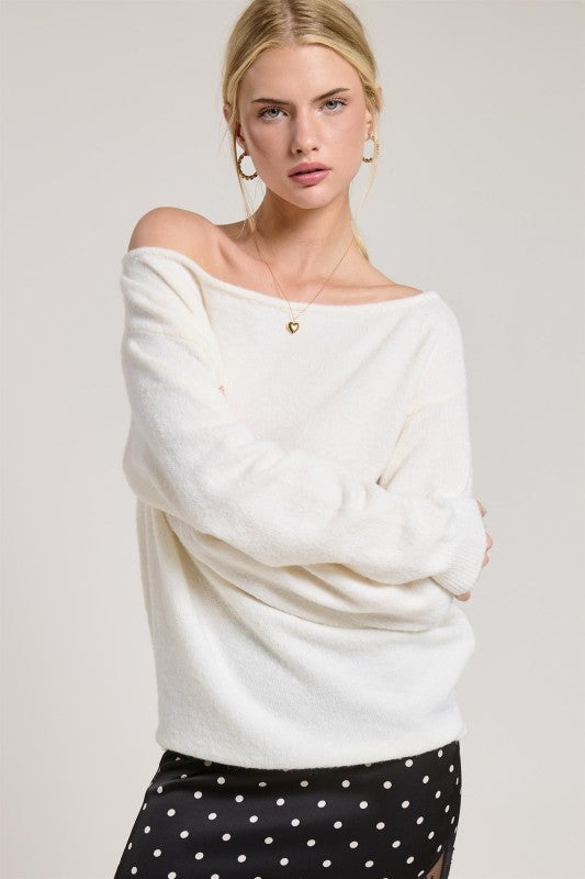 Woman wearing a white off-shoulder sweater with a plain background