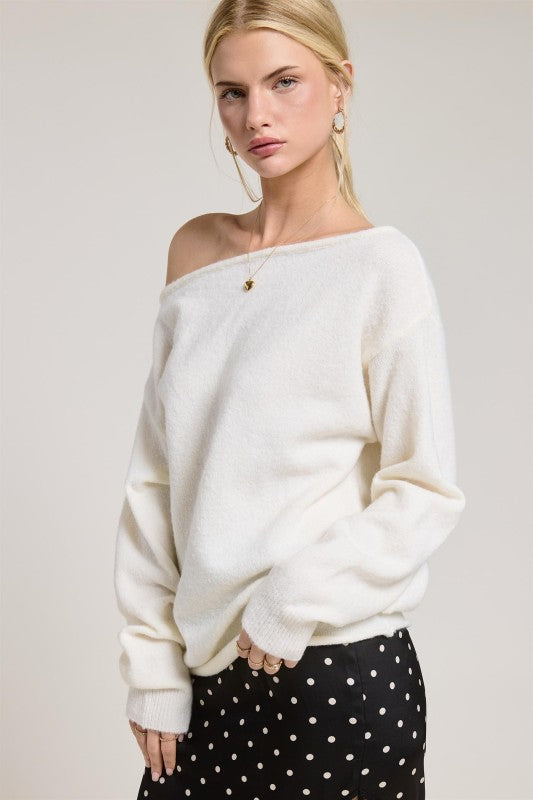 Woman wearing a white off-shoulder sweater against a plain background