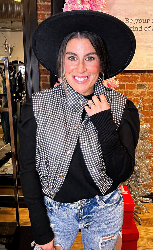 Black and white cropped fit puffer vest with snap closures and stretchy waistband.