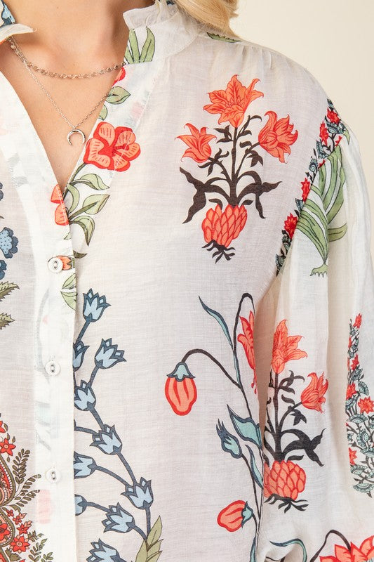 Close-up of a floral patterned shirt with red, orange, and green flowers on a white background.